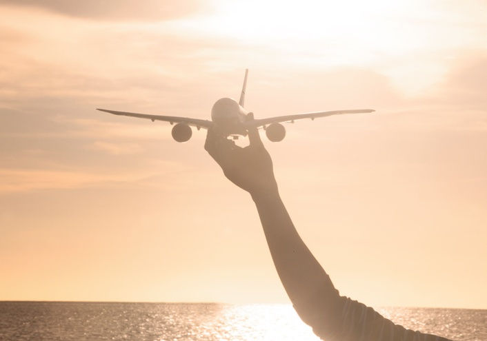 Person holding a model airplane against a sunset sky, representing the dream of learning to fly and starting flight training.