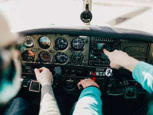 Flight instructor and student pilot reviewing aircraft instruments inside a training airplane cockpit.