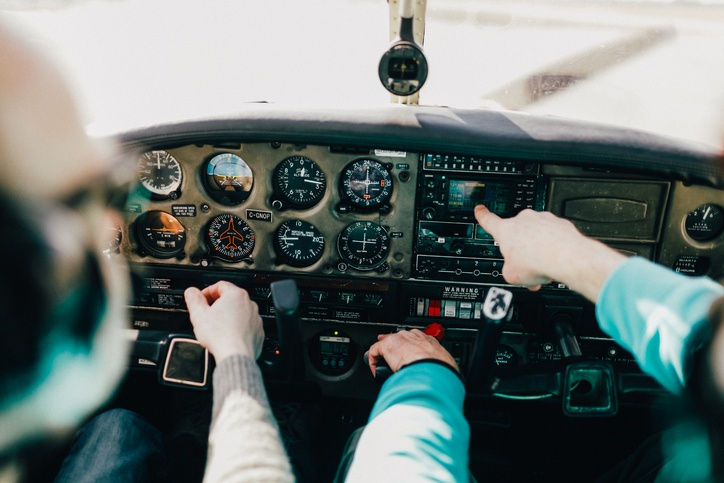 Flight instructor and student pilot reviewing aircraft instruments inside a training airplane cockpit.