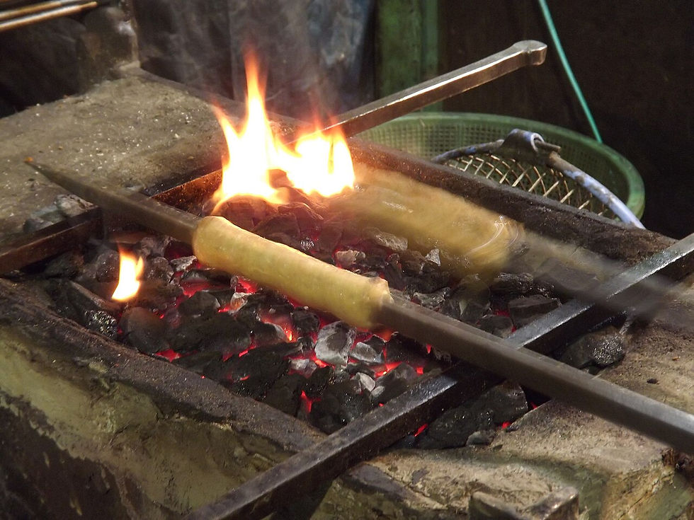 Seekh kebabs being shaped and grilled at a street stall.
