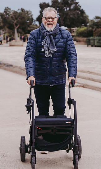 An Elderly man with a walker outdoors with caregiver.