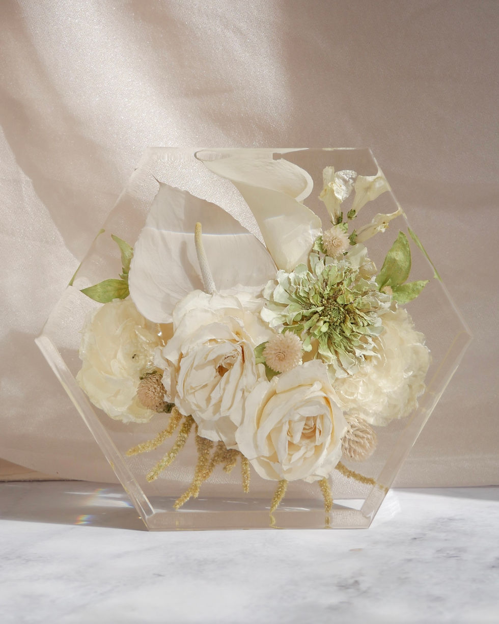 Eye-level view of a polished resin flower keepsake on a wooden shelf.