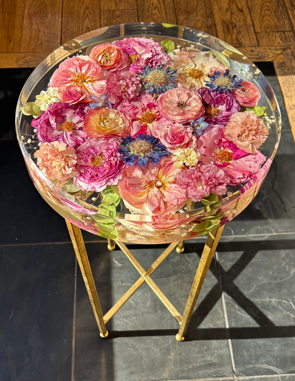 Three-quarter view of a round resin flower table with a black metal base.
