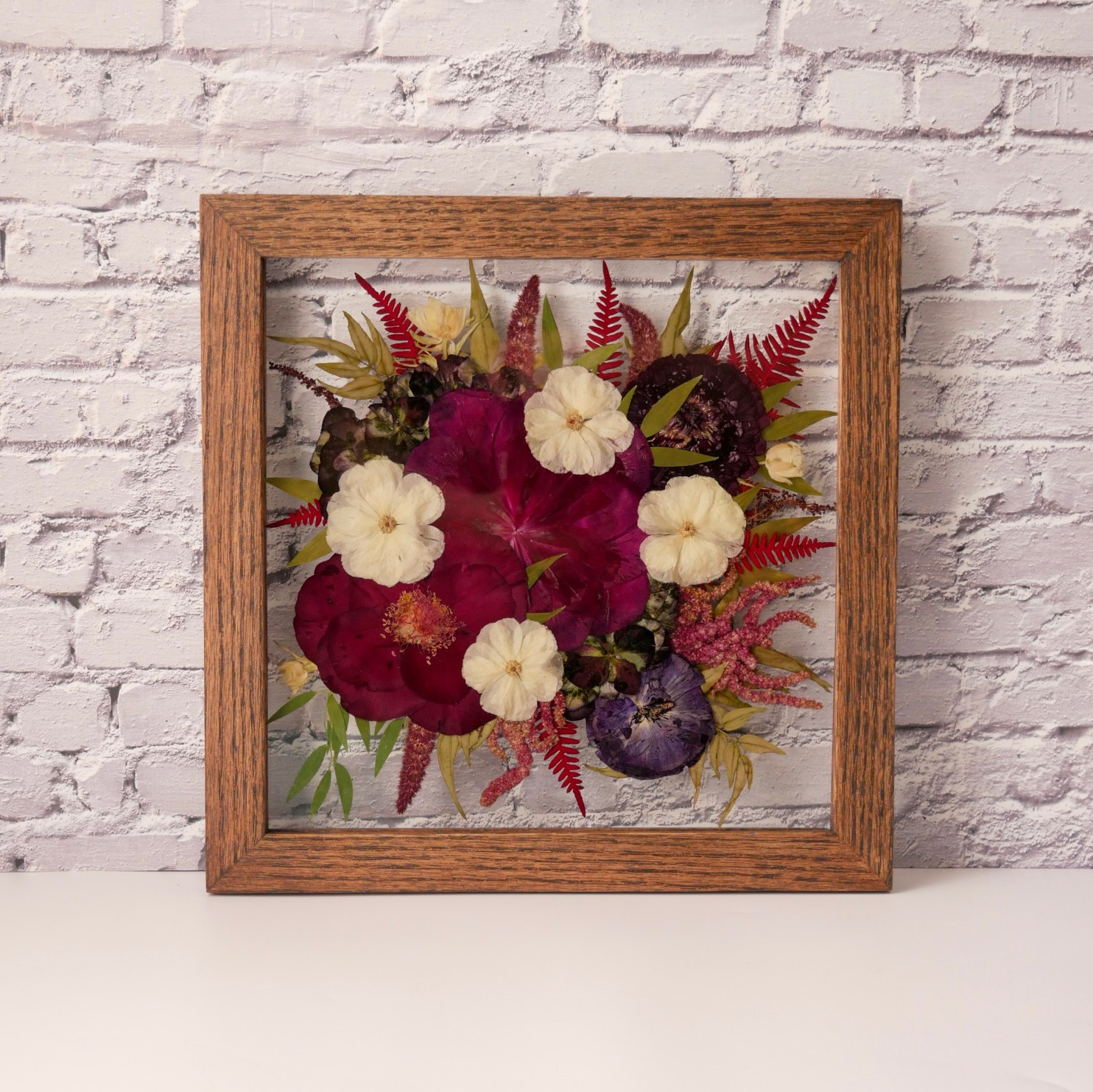 High angle view of a large pressed flower frame with laminated invitation and gold flakes