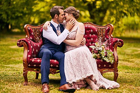 Bride & groom on red lounge at Burnham Grove Estate Camden