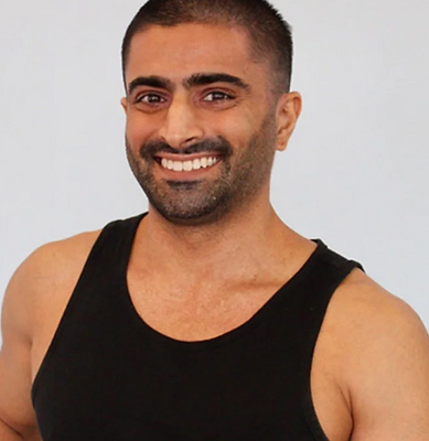 Headshot of Rehan Mahmood, wearing a black sleeveless shirt, standing in front of a light grey background