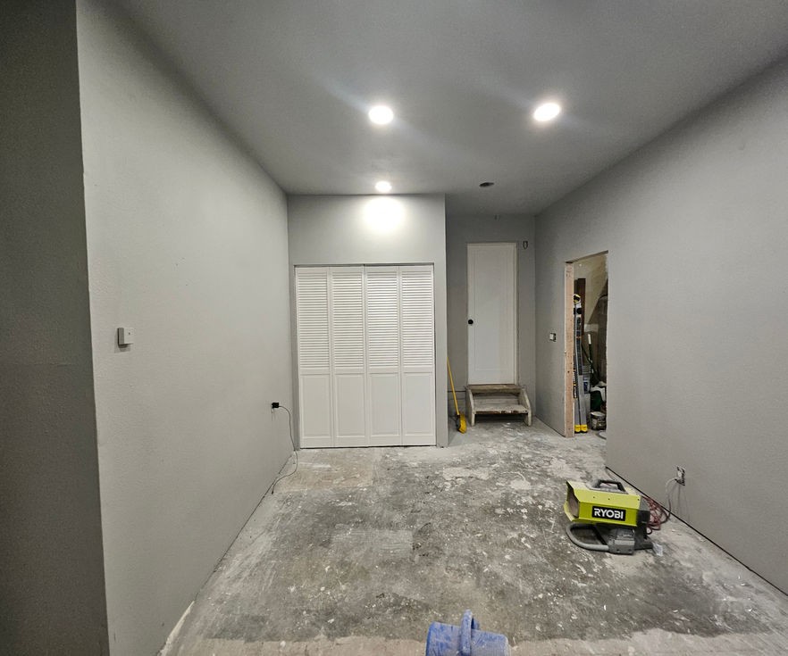 Interior view of garage with painted walls, louvered utility closet doors, and mounted lighting.
