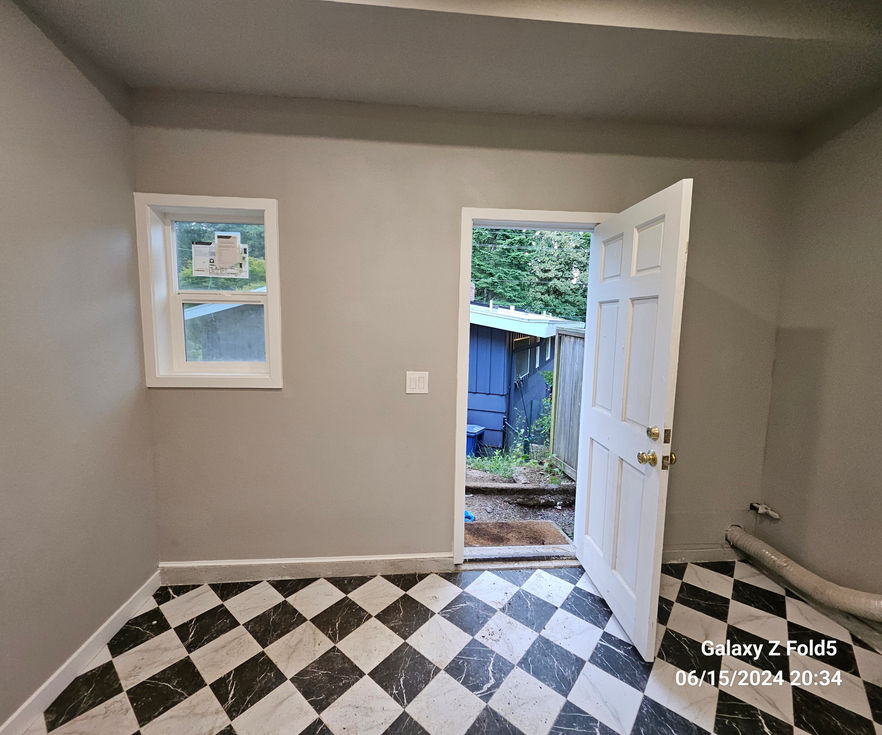 Interior view of laundry area with new window, trim, and existing exterior door.