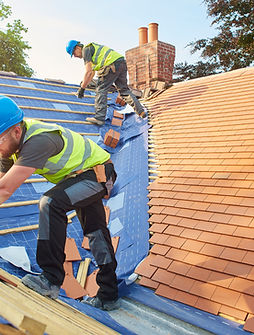 Roofers fitting and repairing roof on building – expert roofing services UK