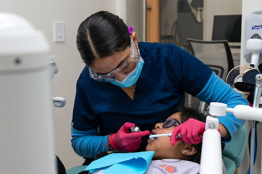 Dental assistant providing professional teeth cleaning for child during pediatric dental visit in Los Angeles
