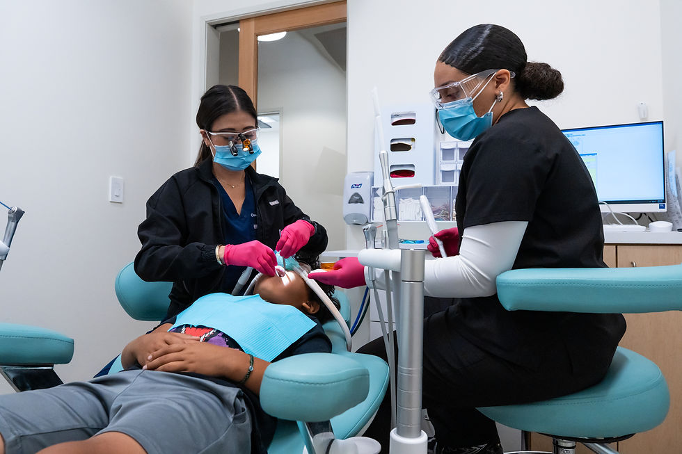 Pediatric dental hygienists at Sola Kids Dental performing a cleaning on a young patient in a modern, child-friendly dental office in South LA.
