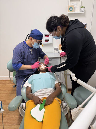 Pediatric dental team treating a child during a routine dental exam, checking for cavities and maintaining healthy teeth in a kid-friendly clinic