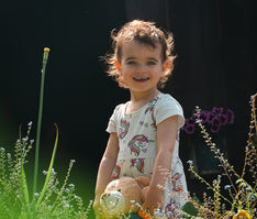 familienshooting portrait von kleinkind mädchen im garten spielend