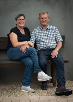 portrait des paares auf bank sitzend vor Hauswand. 