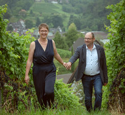 Paar läuft händchen haltend in den Weinreben .