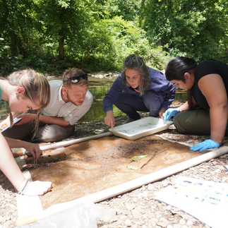 Facilitator and students examine sediment at the river
