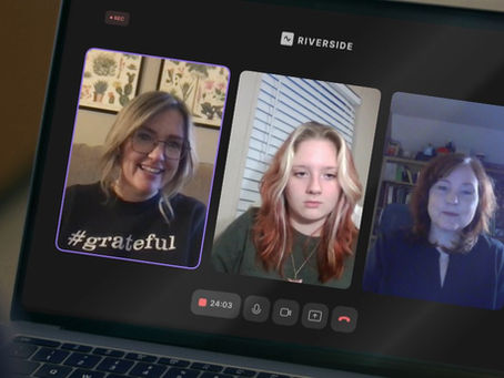 Three women on a video call; one smiling, one neutral, one attentive. "#Grateful" shirt visible. Backgrounds show art, blinds, and shelves.