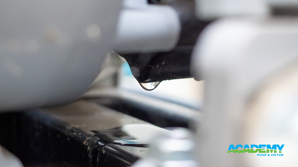 Close-up of a water droplet hanging from a black surface, set against a blurred gray and white background. "ACADEMY PUMP & MOTOR" text in blue.