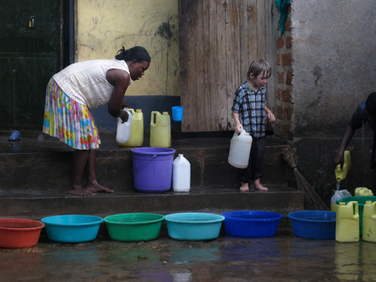 Kurtz children collecting water with their neighbours in Uganda during a rainstorm.