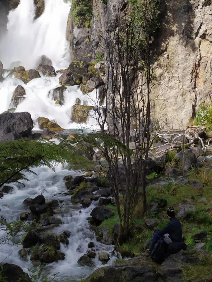 Learner sits beside Tarawera Falls, reflecting on the natural environment during a Travel Ed programme focused on geology, waterways, and cultural significance.
