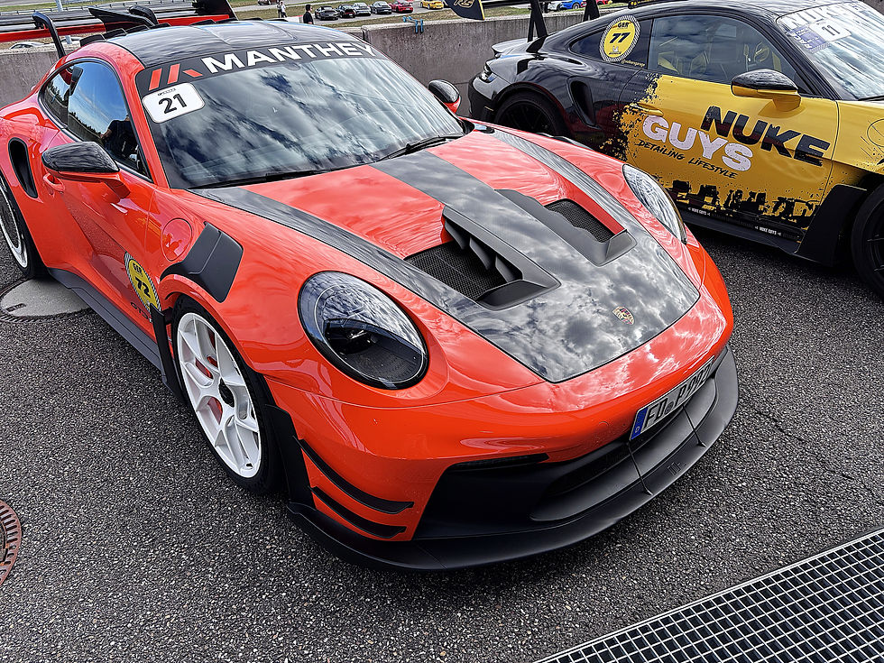 Zwei Porsche-Rennwagen stehen an der Box: roter MANTHEY Nr. 21 und gelb-schwarzer NUKE GUYS Nr. 77.