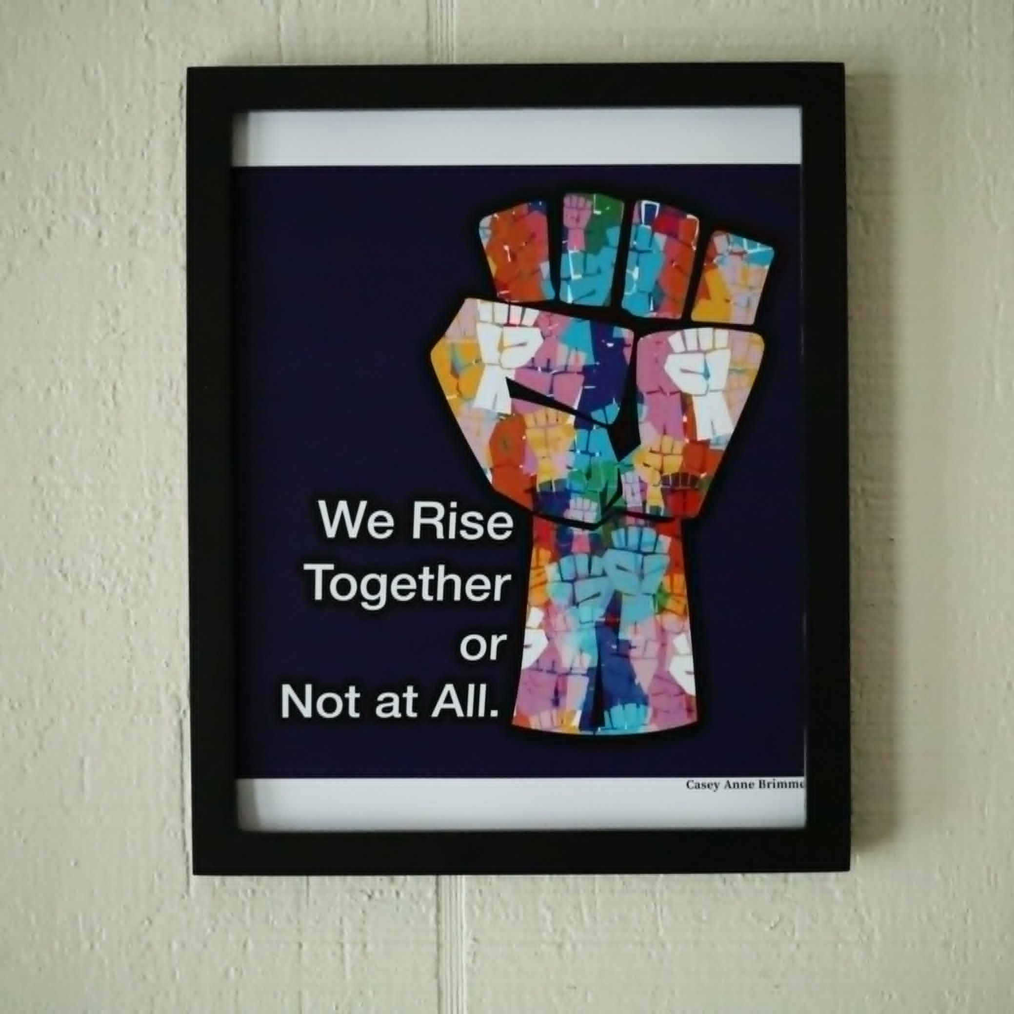 Image of social justice fist made up of many smaller fists in different colors with text We Rise Together or Not At All