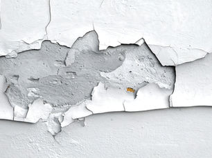 Close-up of peeling paint on a wall, showing signs of damage.