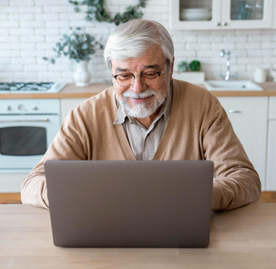 a senior citizen on his laptop computer in the kitchen