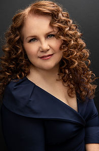 Elegant redhead smiling in a navy dress during a confidence-building portrait session in Central Florida
