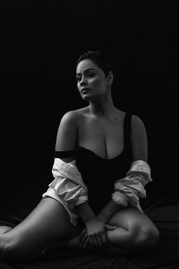 Black and white seated portrait of a woman in a bodysuit with dramatic light, luxury beauty portraits in The Villages, FL.