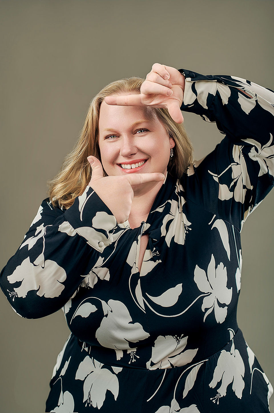 Amanda laughing with her hand in her hair, wearing a floral dress and looking joyful.