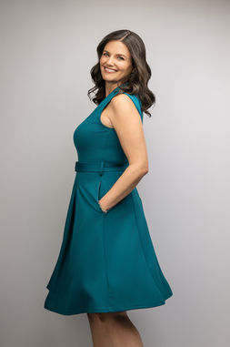 Brittney Elliott standing portrait in teal dress for financial coaching brand