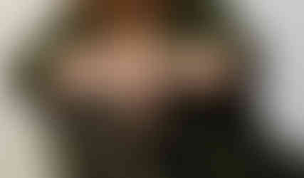 Professional headshot of a confident woman with light blonde hair, wearing a green blazer and a warm smile, captured in a studio setting for personal branding.