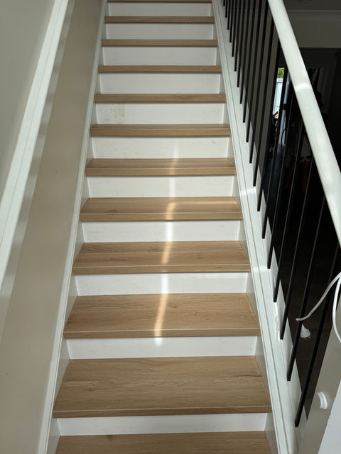 Modern Hybrid SPC stair case with white risers. Accentuates the natural colour of each tread. Paired with darker tones like this Andesite Hybrid Tile, allows the stairs and flooring to complement each other.
