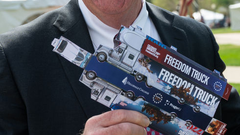 A man holds a cut out paper truck ready for assembly.