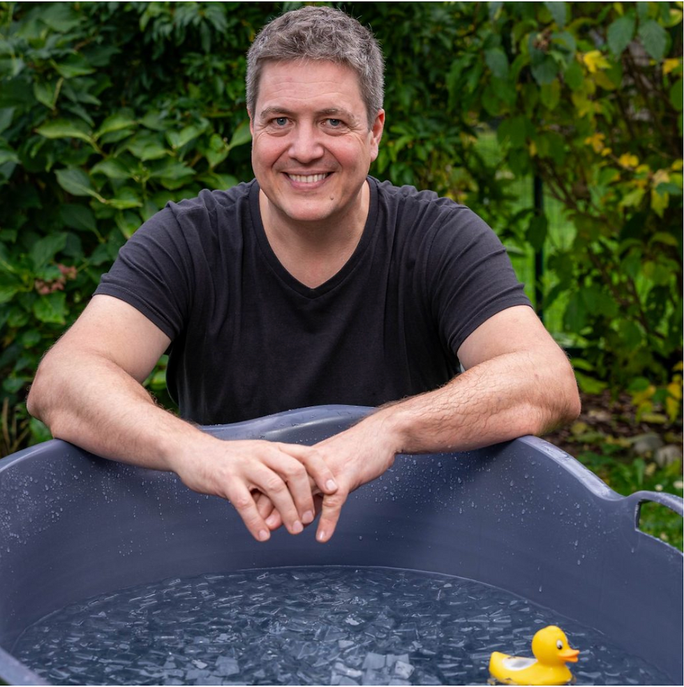 Bernhard beim Eisbaden-Setup im Garten: Eiswasser im großen Behälter und eine gelbe Quietscheente.