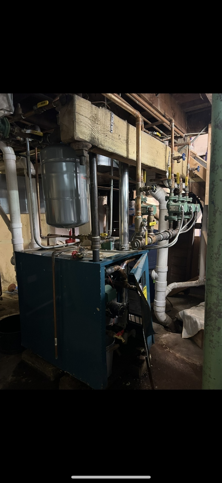 Before replacement: existing floor-standing boiler with expansion tank and heating circulators