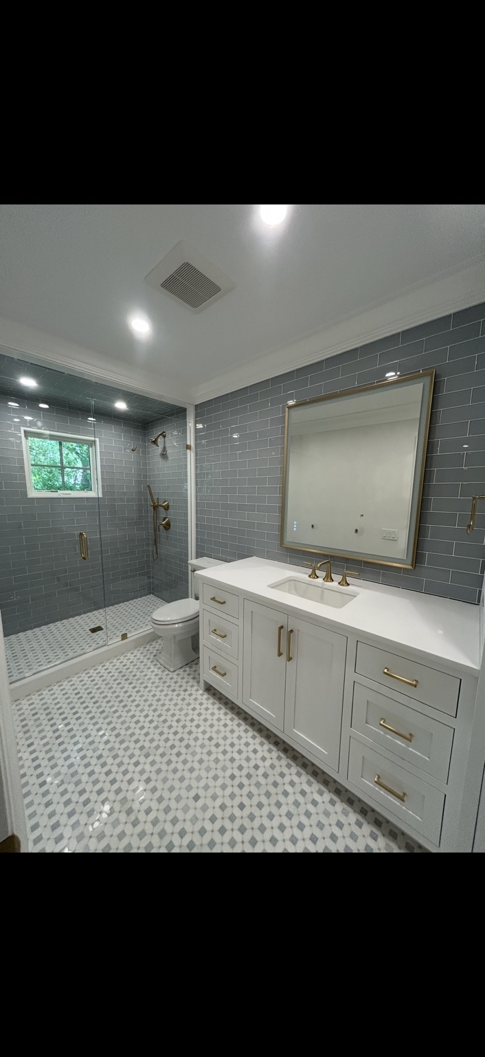 Finished bathroom with white vanity brass plumbing fixtures and glass shower enclosure