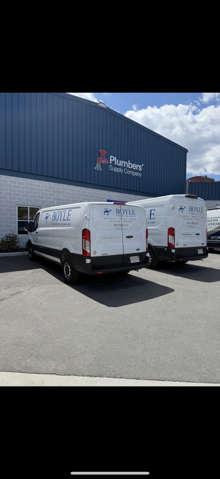 Two Boyle Plumbing Solutions vans outside a plumbing supply store