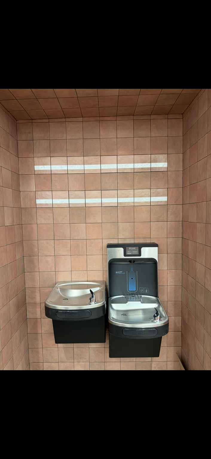 Elkay bottle filling station and two drinking fountains mounted on a tiled wall