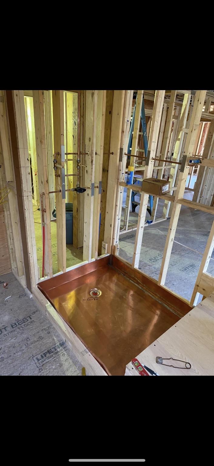Copper shower pan and shower supply piping installed within exposed wall framing