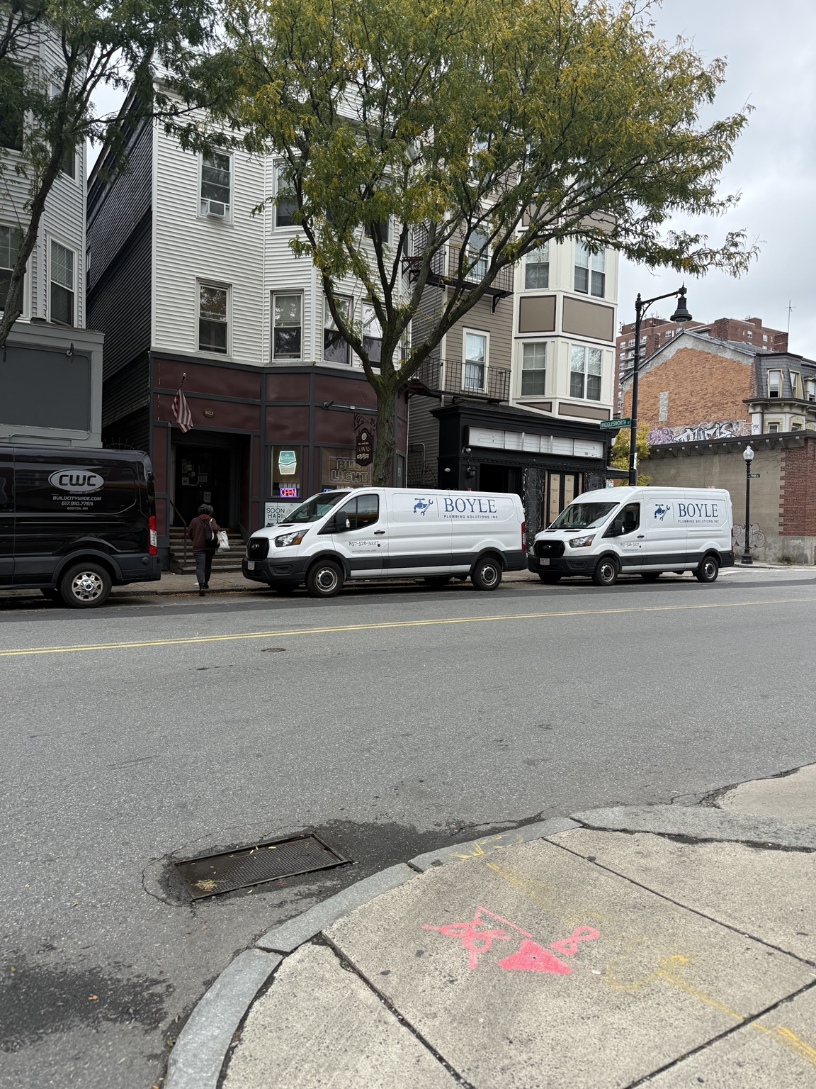 Two Boyle Plumbing Solutions service vans parked outside city buildings