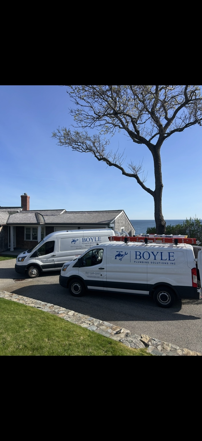 Two Boyle Plumbing Solutions service vans parked at a residential property