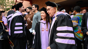 Graduate posing with professor outside after graduation