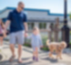 A Family walking in Downton gig harbor with a golden colored dog.