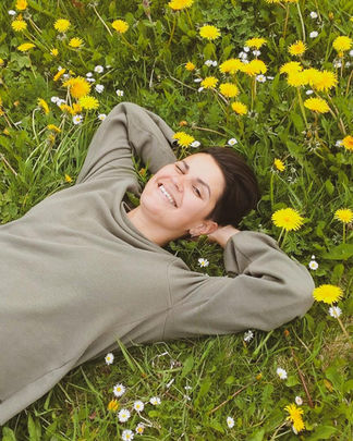 Smilende kvinne liggende i løvetann blomstereng