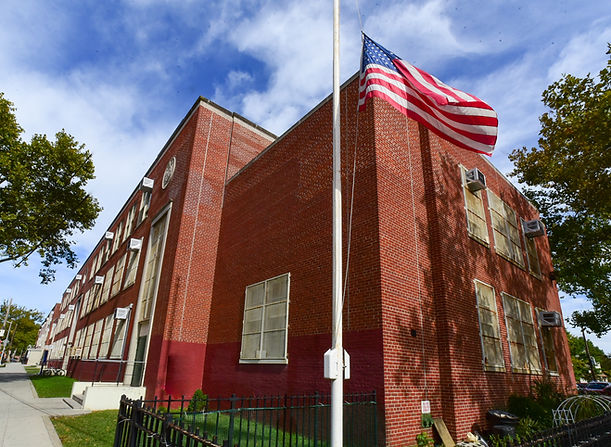 school in the background and an American flag on a pole in the foreground