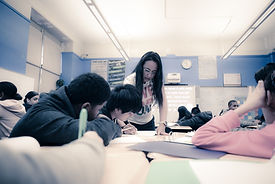 teacher helping group of students in a classroom
