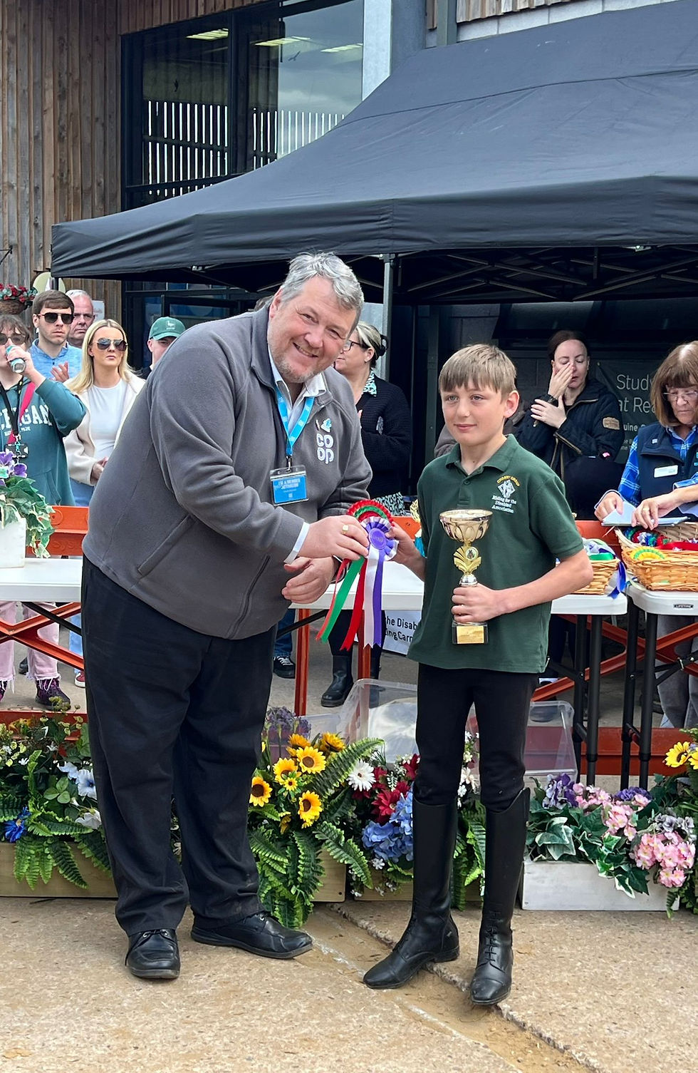 Boy wearing Crosby RDA t-shirt being presented with red rosette and trophy.
