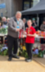 Photo of rider wearing red top with Isle of Man logo receiving a red rosette  and trophy.